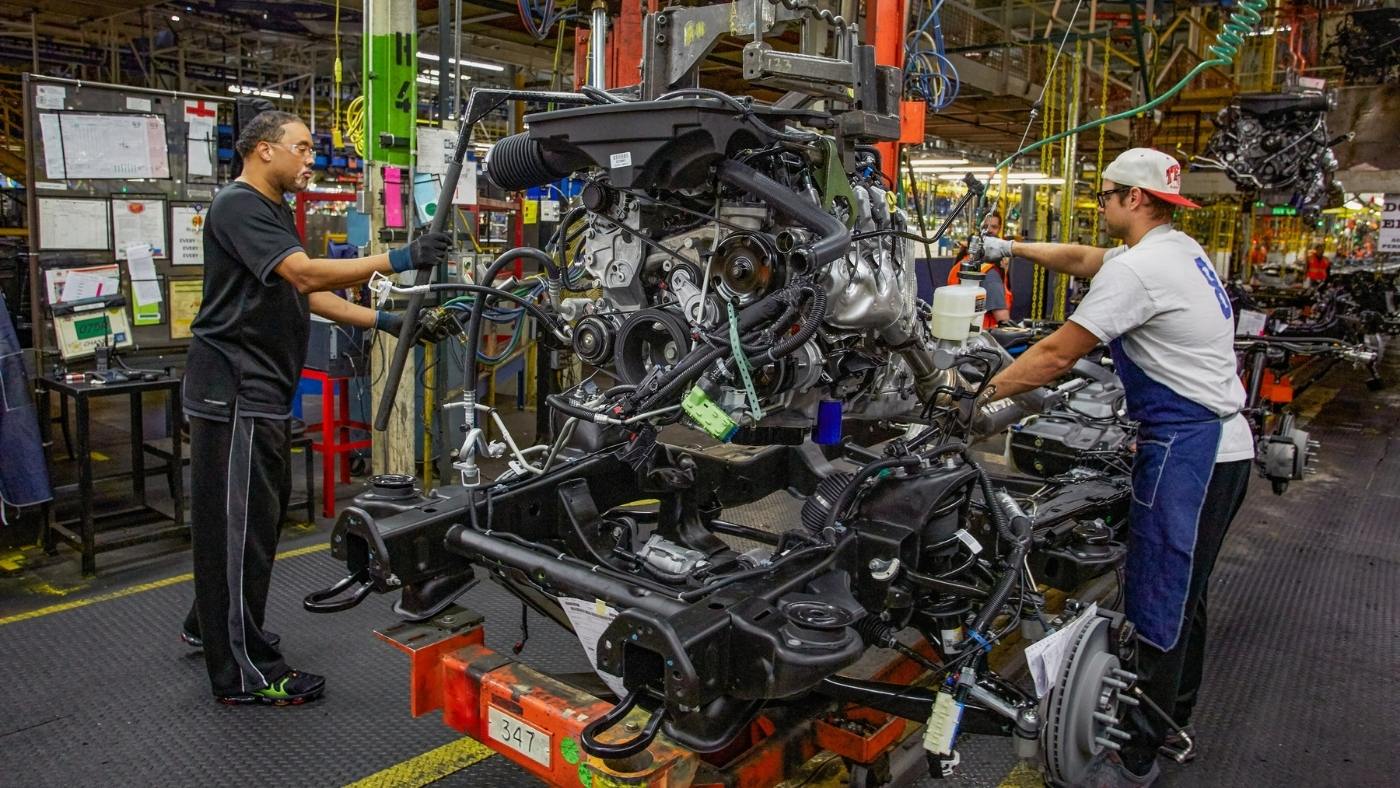 two production employees work together in a manufacturing plant