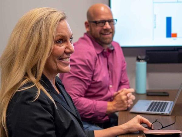 Two GM employees smiling during a meeting.