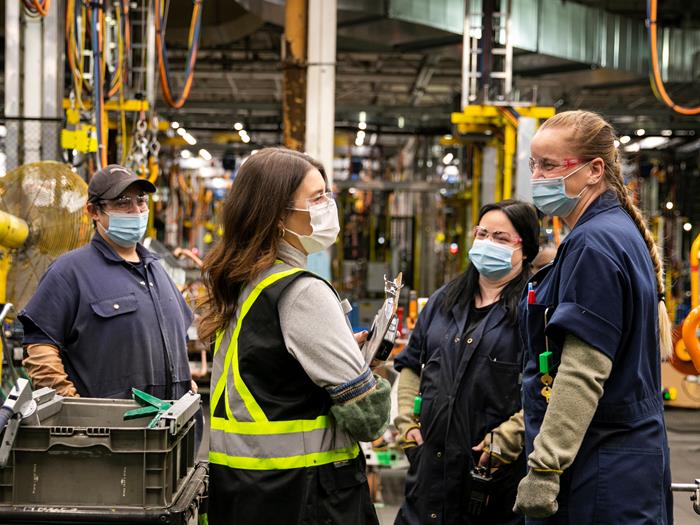 A group of co-op students talk together in a manufacturing plant