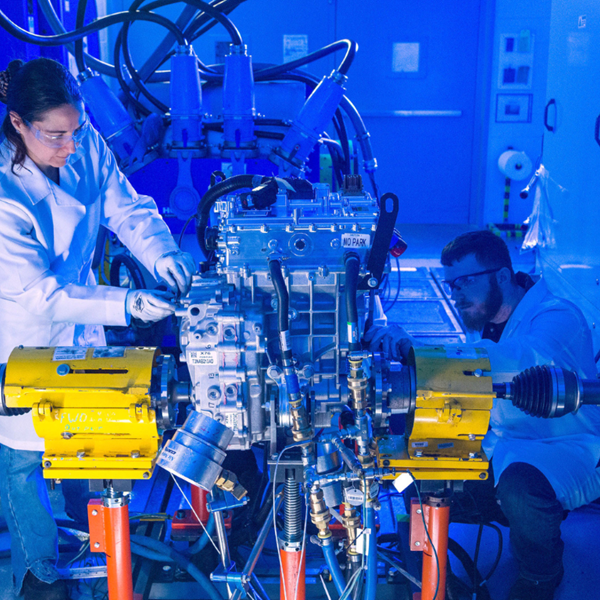 Workers in safety glasses and lab coats working technical machine