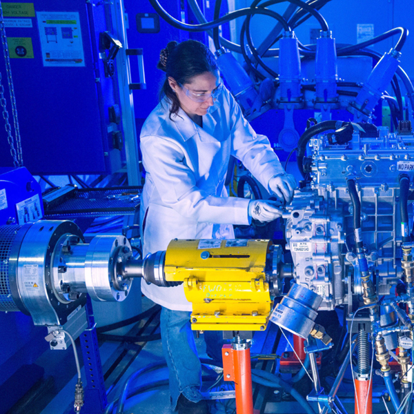 Workers in safety glasses and lab coats working technical machine