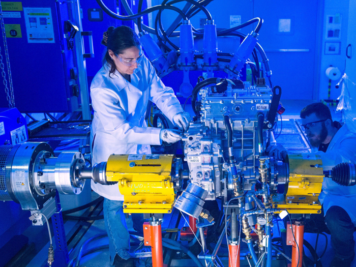 Workers in safety glasses and lab coats working technical machine