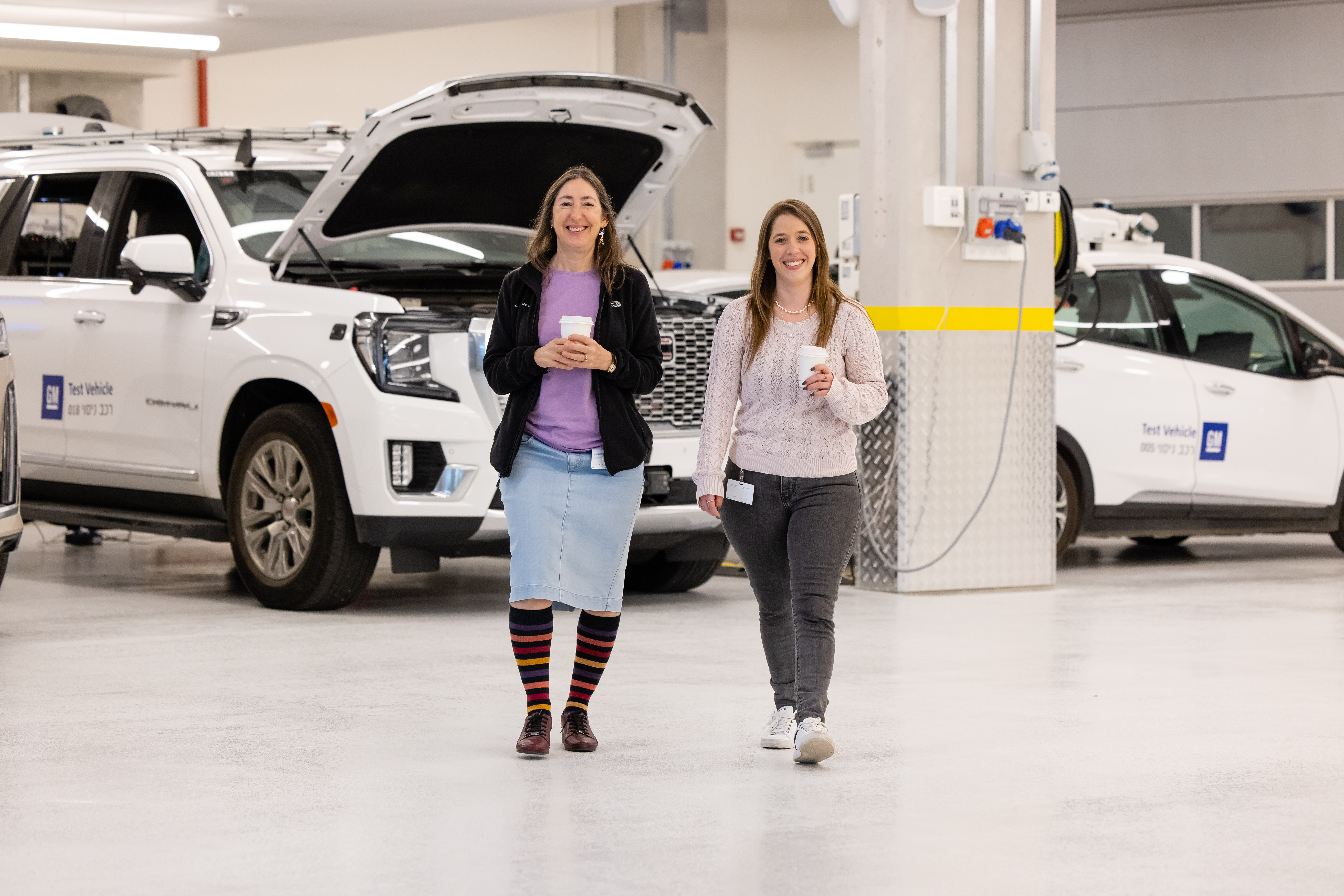 Female employees walking with coffee in front of vehicles