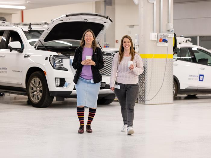 Female employees walking with coffee in front of vehicles