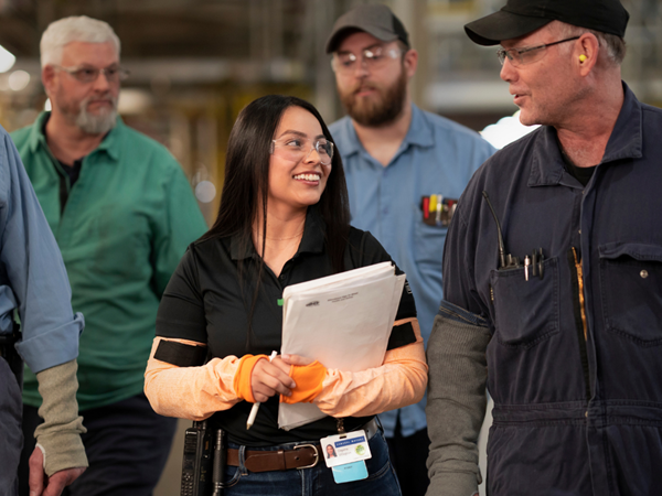 Woman in safety glasses smiling in manufacturing plant