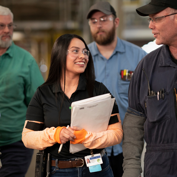 Woman in safety glasses smiling in manufacturing plant