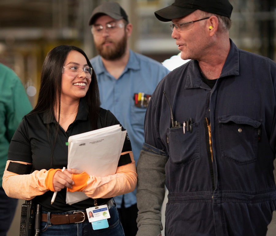 Woman in safety glasses smiling in manufacturing plant