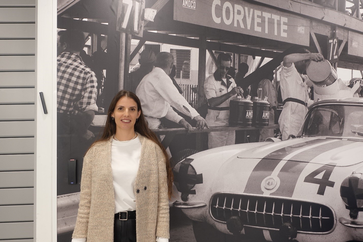 A person standing in front of a picture of a car

Description automatically generated, Picture