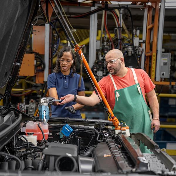 Man and woman with safety glasses working on engine